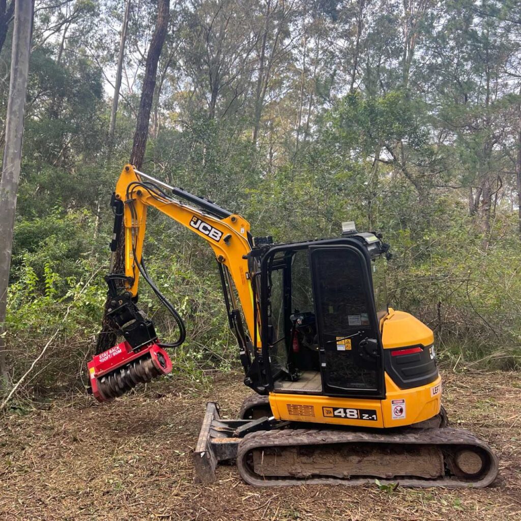Forestry mulching excavator clearing land for firebreak in rural property in NSW.